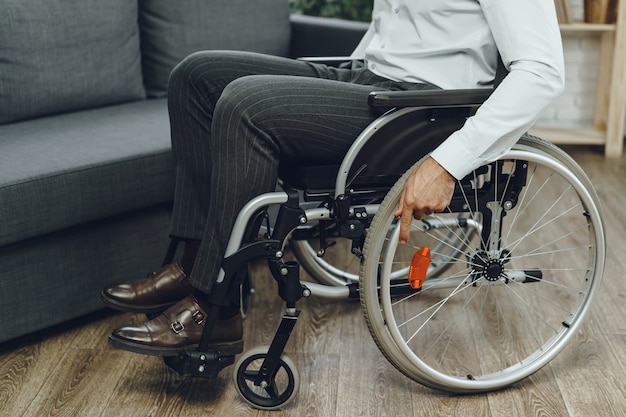 Hombre discapacitado intenta sentarse en un sofá desde silla de ruedas