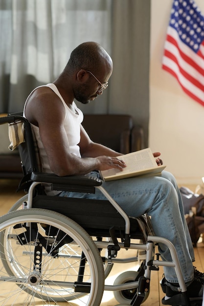 Foto hombre discapacitado leyendo un libro en casa