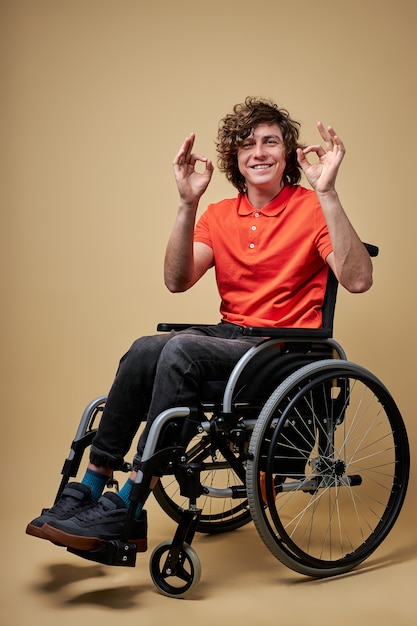 Hombre discapacitado mostrando gesto ok, rizado hombre caucásico sonriendo, no se rinde, retrato aislado