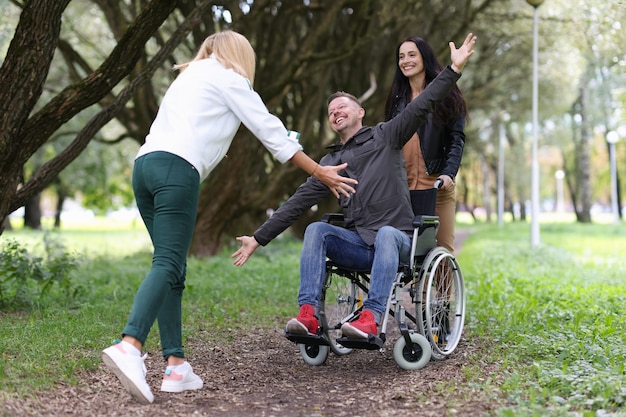 Hombre discapacitado en silla de ruedas caminando en el parque con la enfermera y abrazando a su novia toda la vida de