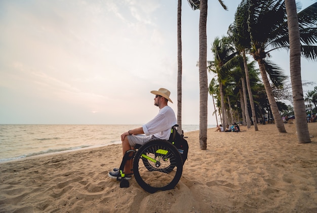 Hombre discapacitado en silla de ruedas en la playa.