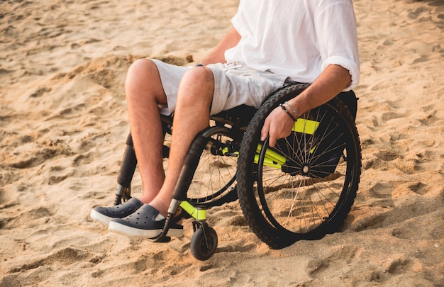 Hombre discapacitado en silla de ruedas en la playa.