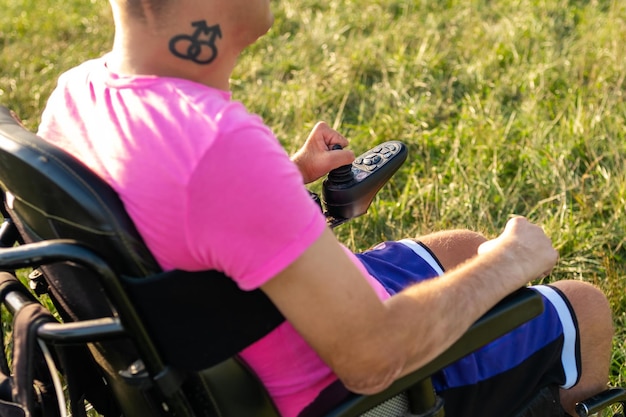 Foto hombre discapacitado con tatuaje lgbt usando joystick en silla de ruedas eléctrica