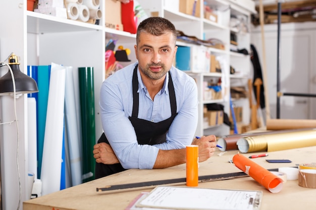 Hombre diseñador y operador de impresión con impresión de papel en la fabricación