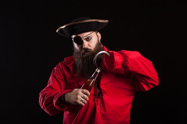 Hombre disfrazado de pirata para halloween abriendo una botella con su gancho. Hombre guapo disfrazado de pirata.