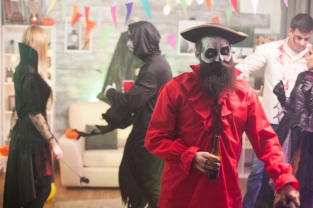 Hombre disfrazado de pirata medieval sosteniendo una cerveza en la fiesta de halloween.