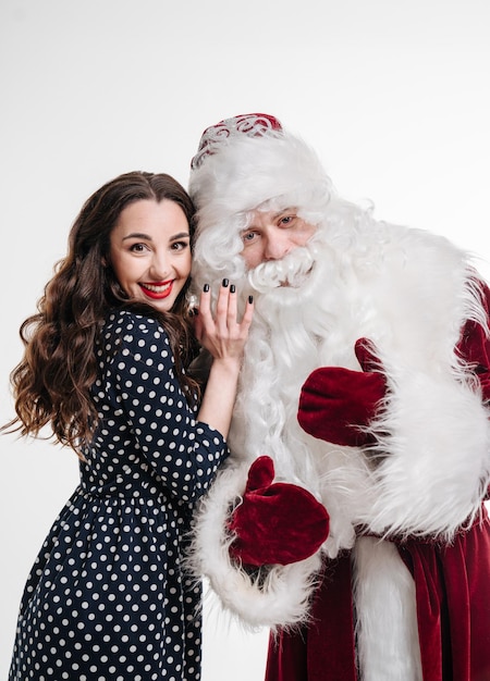 Hombre disfrazado de santa claus y hermosa niña sobre fondo blanco Mujer con santa claus juntos vacaciones de Navidad y concepto de personas