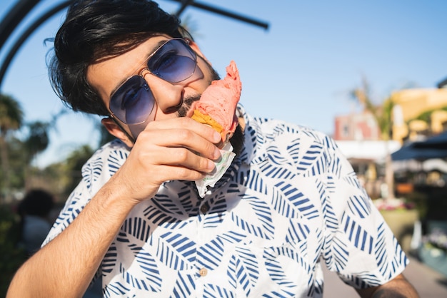 Hombre disfrutando el clima soleado mientras come un helado