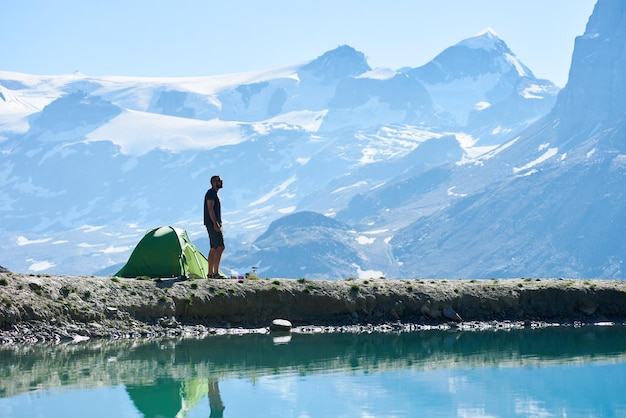 Hombre disfrutando del paisaje de las montañas cerca de la tienda