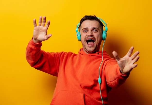 Hombre disgustado con auriculares en pared amarilla