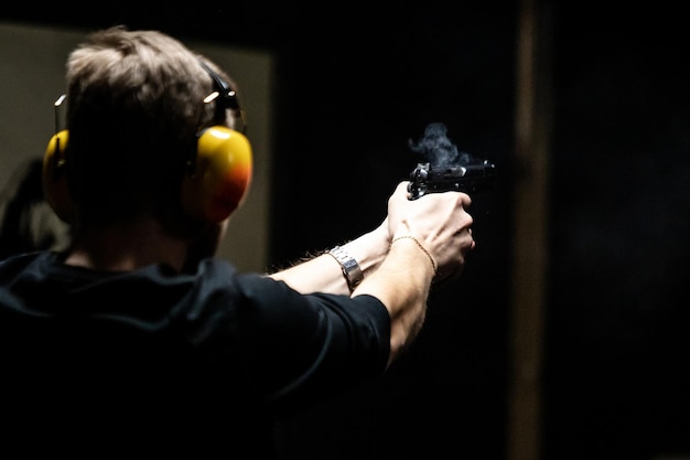 Foto hombre disparando una pistola a distancia interior con humo de boquilla capturado