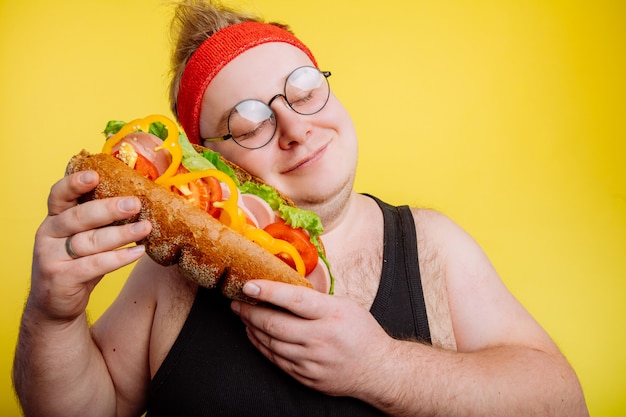 Hombre divertido abraza una hamburguesa enorme