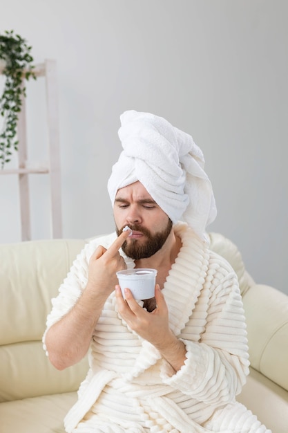 Hombre divertido aplicando crema eficaz en su spa de piel facial en casa cuidado de la piel y el cuerpo para hombres