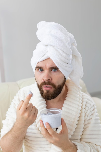 Hombre divertido aplicando crema eficaz en su spa de piel facial en casa cuidado de la piel y el cuerpo para hombres