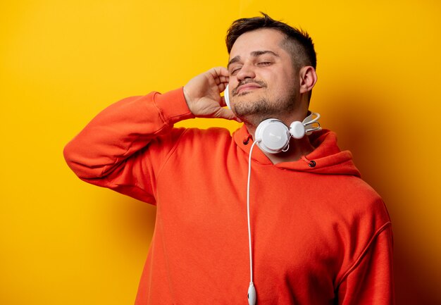 Hombre divertido con auriculares en pared amarilla