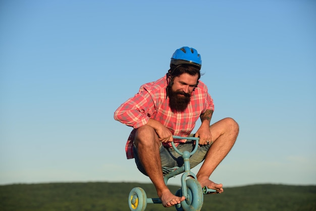 Hombre divertido en una bicicleta para niños. Ciclista nerd montando.