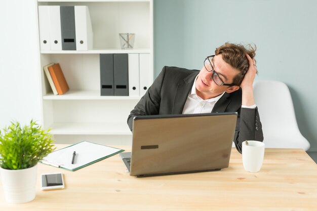 Hombre divertido cansado después de trabajar en la computadora en la oficina