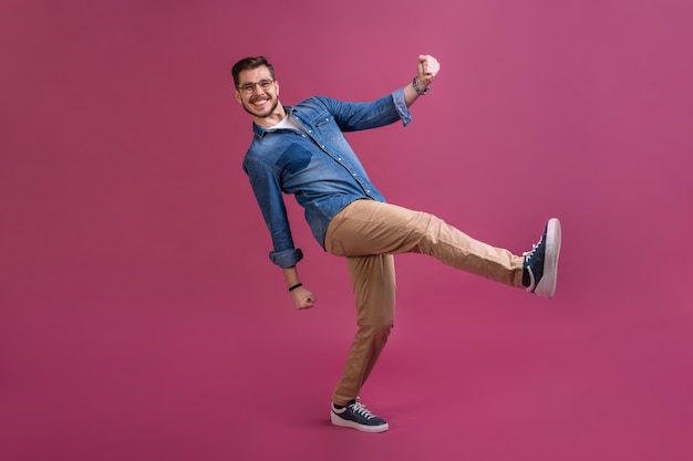 Foto hombre divertido en casual se está divirtiendo. está posando y bailando. aislado sobre fondo rosa.