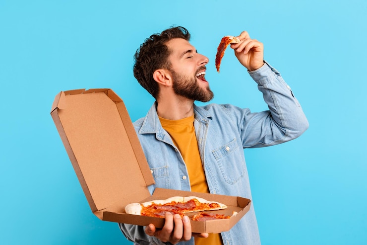 Foto hombre divertido comiendo en exceso comida chatarra comiendo una porción de pizza studio