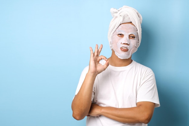 Hombre divertido con máscara de cosméticos en la cara sobre fondo azul.