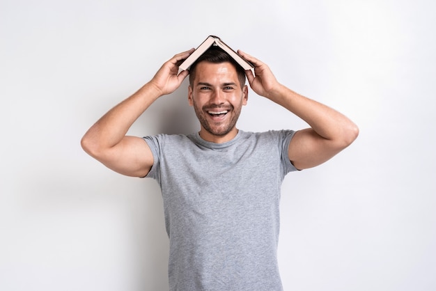 El hombre divertido puso el libro en su cabeza y felizmente mirando a la cámara.