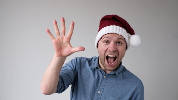 Hombre divertido en un sombrero de año nuevo cuenta los dedos como muestra números