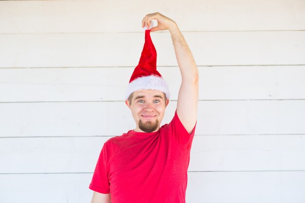 Hombre divertido en traje de santa posando en la pared blanca