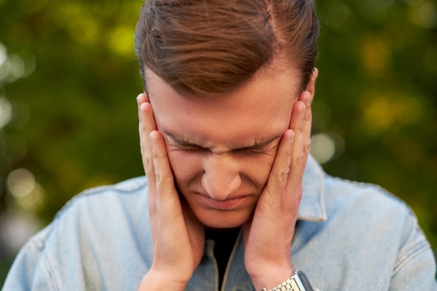 Hombre con dolor de cabeza, migraña o estrés. Ayuda, problemas de comunicación, concepto de exceso de trabajo