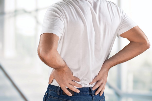 Hombre con dolor de espalda en el fondo de la ventana