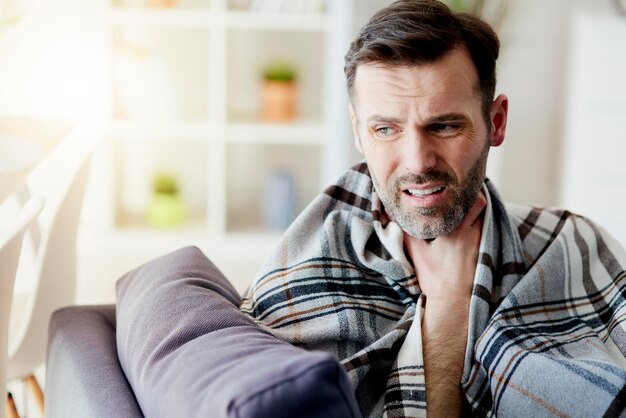 Foto hombre con dolor de garganta quedándose en casa