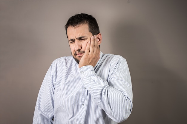 Hombre con dolor lanzando su mano a su cara