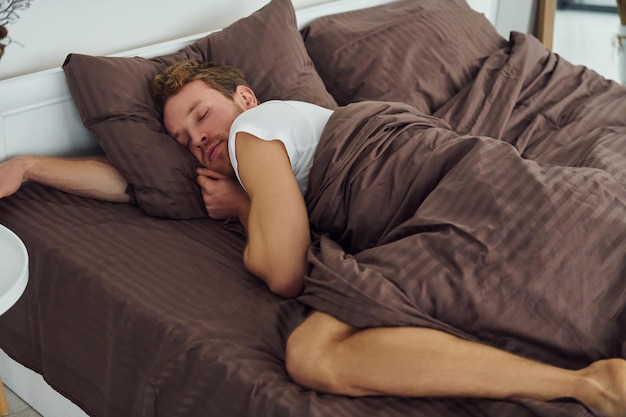 El hombre duerme en la cama Interior y diseño de un hermoso dormitorio moderno durante el día