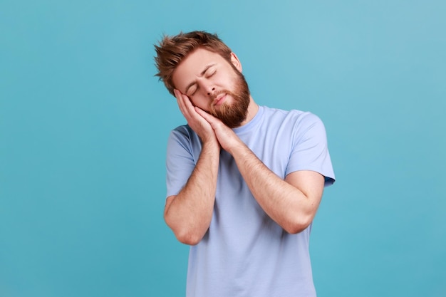 Hombre durmiendo acostado en sus palmas y sonriendo complacido cómodo siesta y descansando durmiendo