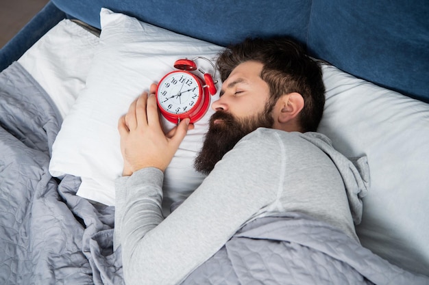 Hombre durmiendo con despertador en la cama hora de dormir