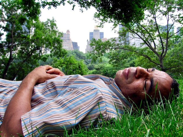 Foto hombre durmiendo en la hierba en la ciudad