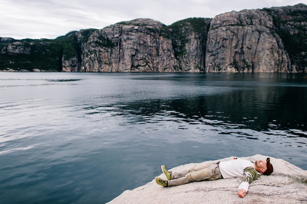 Hombre durmiendo en piedra en las montañas en el fiordo