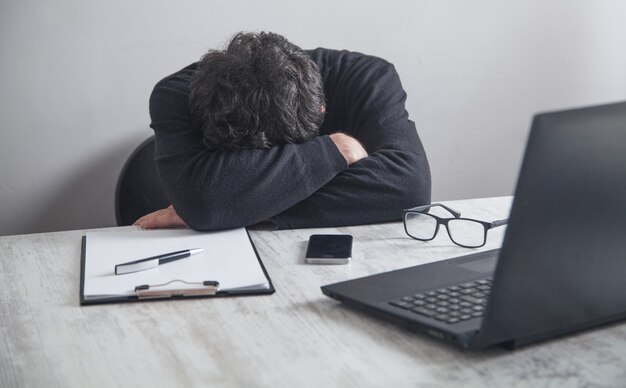 Hombre durmiendo sobre el lugar de trabajo en su escritorio