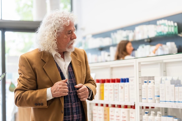Hombre de edad avanzada comprando en una farmacia con estantes de varios productos en el fondo