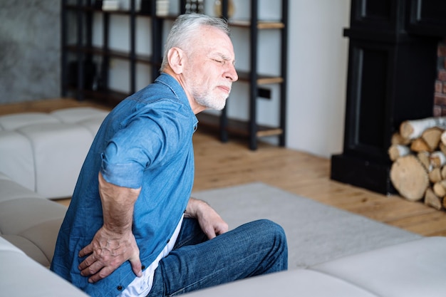 Hombre de edad avanzada que siente dolor y tiene inflamación de la osteocondrosis lumbar
