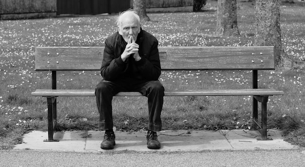 Foto hombre de edad avanzada sentado en un banco en el parque