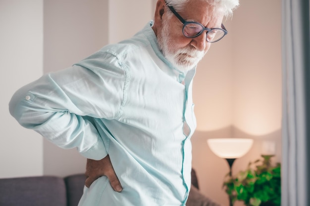 Hombre de edad avanzada siente dolor de espalda repentino, dolor muscular, lesión por tensión en el hogar, dolor lumbar en la parte inferior de la espalda.
