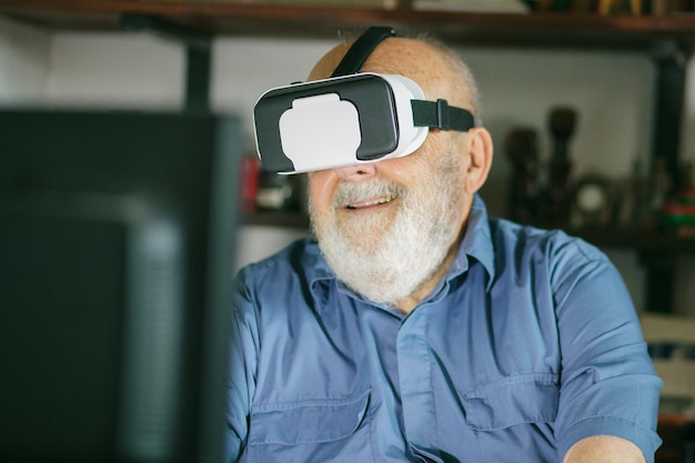 Hombre de edad avanzada usando simulador de realidad virtual y computadora