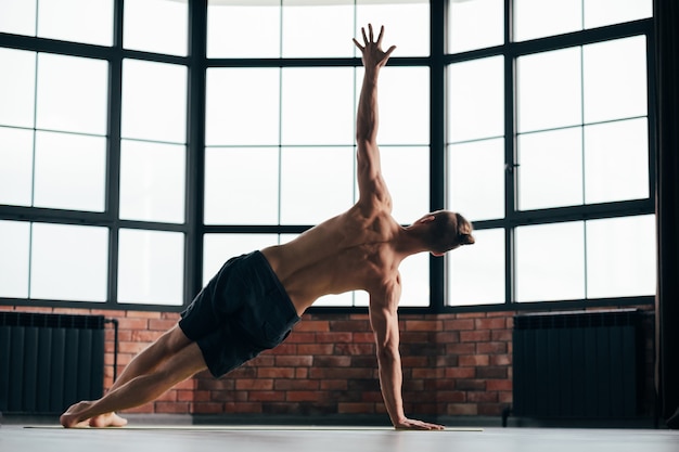 hombre ejercicio asana perro hacia abajo en el gimnasio.