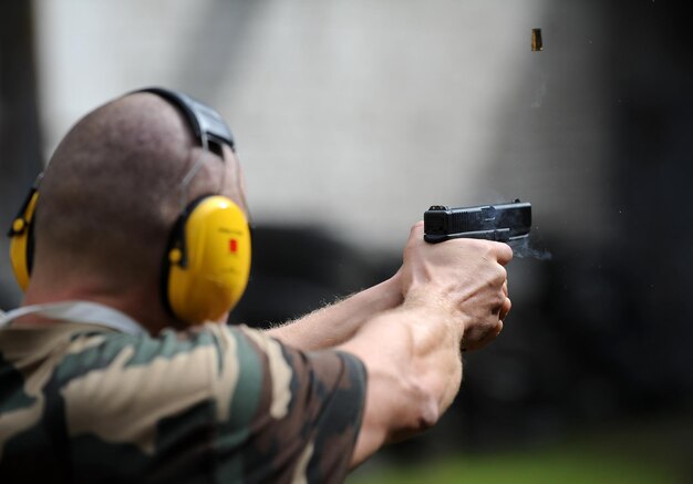 Hombre del ejército disparando un arma al aire libre