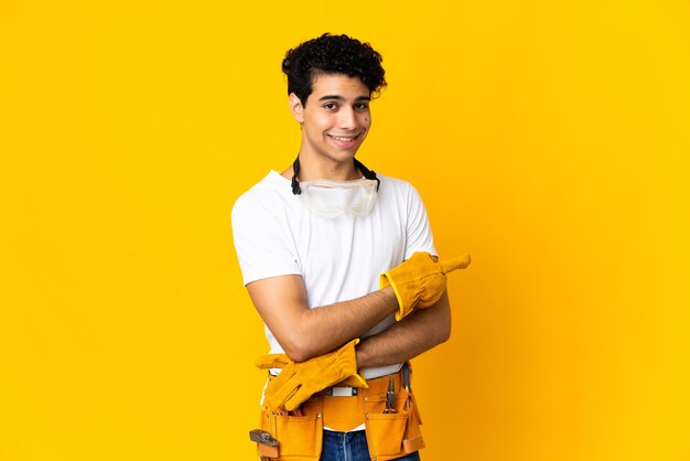 Hombre electricista venezolano aislado sobre fondo amarillo dedo acusador hacia el lado