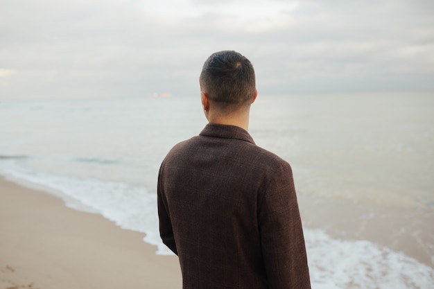 Hombre elegante en el abrigo admirando la hermosa vista. Él admira la vista de un hermoso paisaje marino.