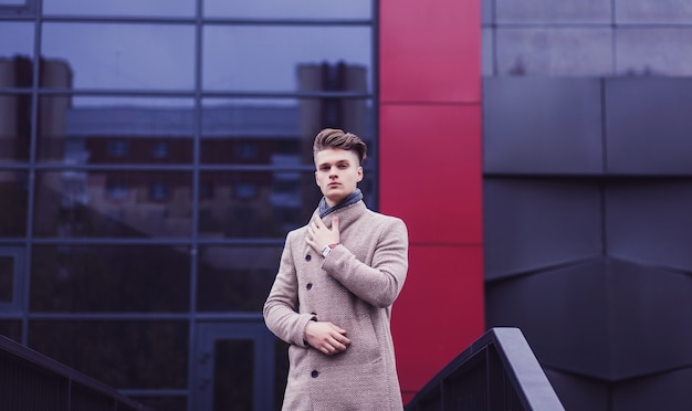 Hombre elegante con un abrigo de otoño y un reloj en la calle de la ciudad