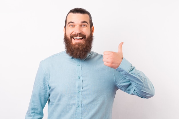 Hombre elegante alegre está mostrando el pulgar a la cámara.