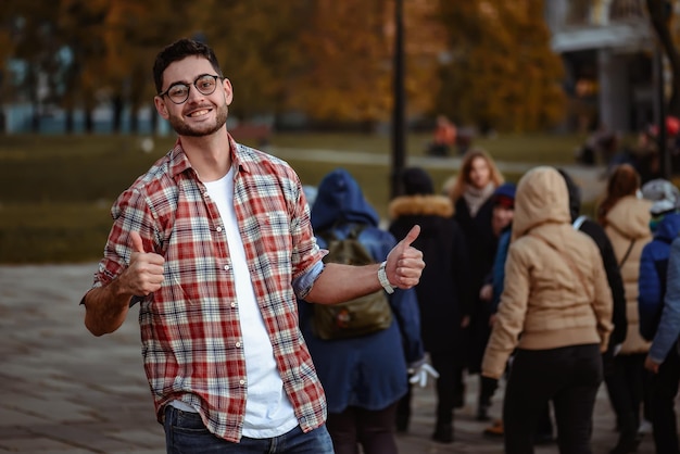 Hombre elegante con barba y gafas de sol de pie en el parque.