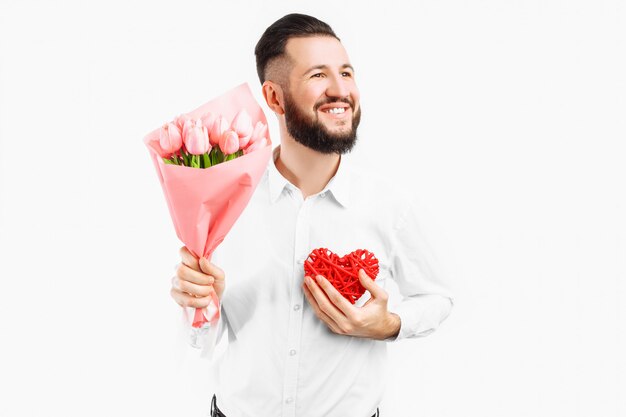 Foto hombre elegante con barba, con un ramo de tulipanes rosados y un corazón rojo de san valentín, un regalo para el día de san valentín